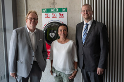  The new defibrillator hangs in the entrance area of the LernWerk. Bernd Kleine-Rüschkamp (from left) from Volksbank Bocholt has now handed over the device to Head of Department Jule Wanders (Education and Culture) and Bocholt's First City Councillor Björn Volmering. 